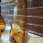 Ravfarvet glasvase vist fra en anden vinkel med en del af en lampe ved siden af.