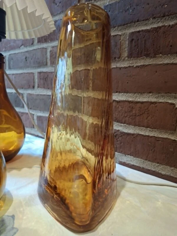 Ravfarvet glasvase vist fra en anden vinkel med en del af en lampe ved siden af.