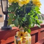 Vasen med gul blomsterdekoration står med en buket gule roser.