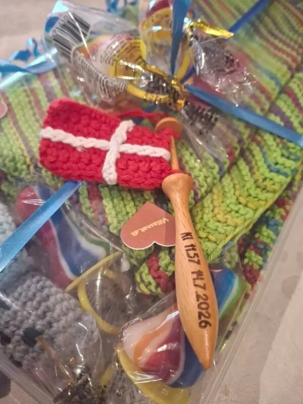 Rødt og hvidt hæklet flag med en dato graveret på træpinden, lagt på en indpakket gave.