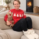 Rød snemandstrøje vist i en lys sofa ved en brændeovn.