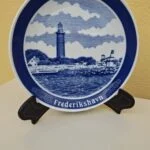 Blå og hvid Frederikshavn årsplatte fra 1980 med fyrtårn, vist på tallerkenholder