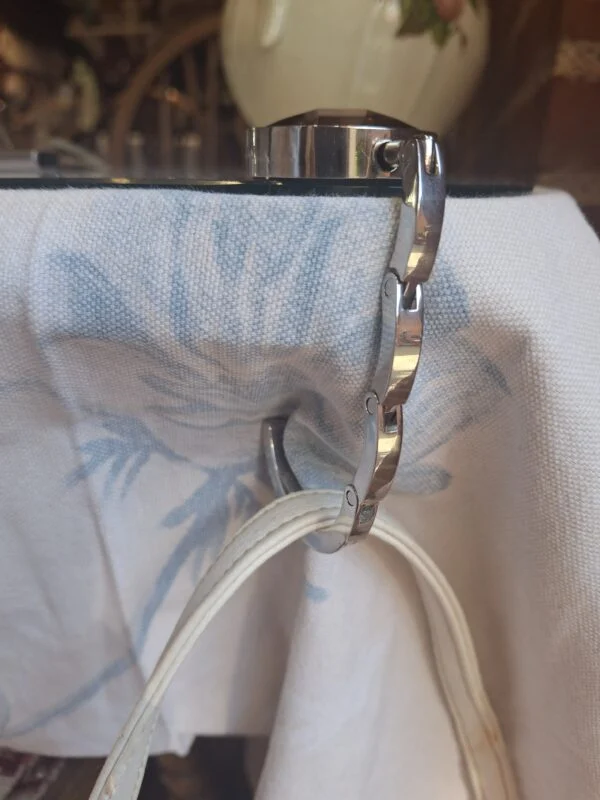 Taskeholder set fra siden med en taskerem hængende på krogen