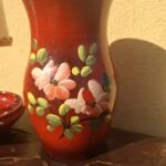 Rød vase med rosa blomster og grønne blade