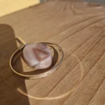 Nærbillede af vedhængets rosa midterdel med fine lyse bånd og vinkler