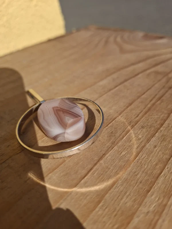 Nærbillede af vedhængets rosa midterdel med fine lyse bånd og vinkler