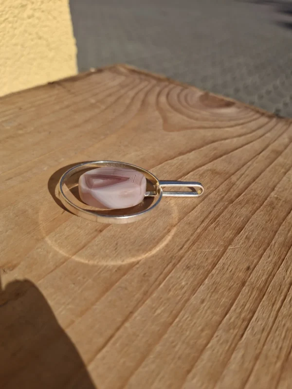 Vedhænget set fra siden med åben oval metalramme og aflangt ophæng
