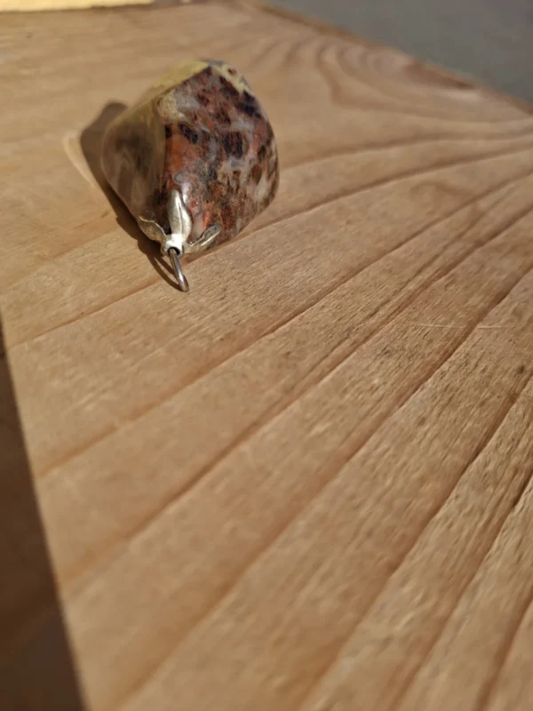 Nærbillede af metalophæng og ring på det rødbrune stenvedhæng