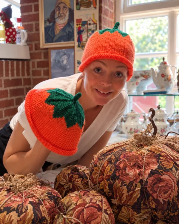 AI-genereret stemningsbillede baseret på VillaSnaks video: en kvinde med orange græskarhue og grøn top i en hyggelig vintagebutik.