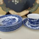 Country Style-kop med underkop ved siden af en stak matchende kagetallerkener