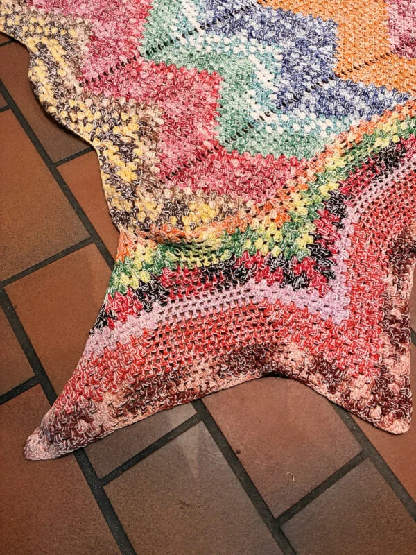 Originalt detaljefoto af zigzagtæppets flerfarvede, spidse kant.