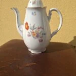 Hvid porcelænskande med låg, farverige blomster, lang tud og guldkant