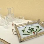 Vintage glasbakke med grønne kløvermotiver, rød dekoration og metalramme med håndtag, vist ved siden af glas