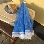 Sammenfoldet blåt fluenet med hvid blondekant ved siden af en bakke