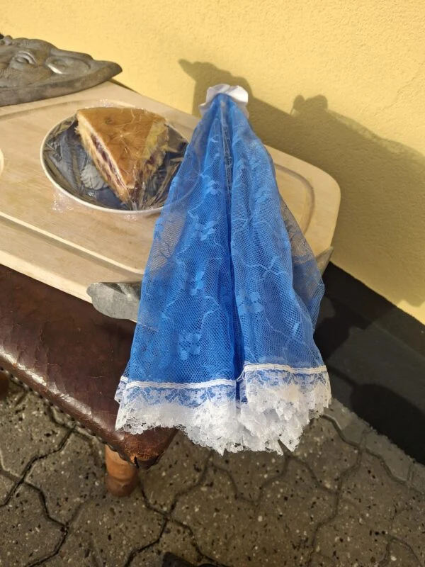 Sammenfoldet blåt fluenet med hvid blondekant ved siden af en bakke