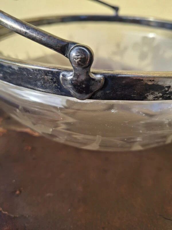Skålens metalrand og hankbeslag med mørk patina og slid
