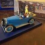 Blå Tintin-paradebil set skråt fra siden med sorte skærme og lyse dæksider