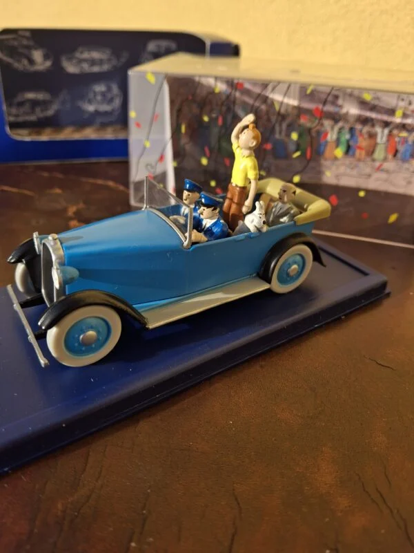 Blå Tintin-paradebil set skråt fra siden med sorte skærme og lyse dæksider