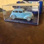Lyseblå Tintin-taxi under klar udstillingskappe med æske bagved