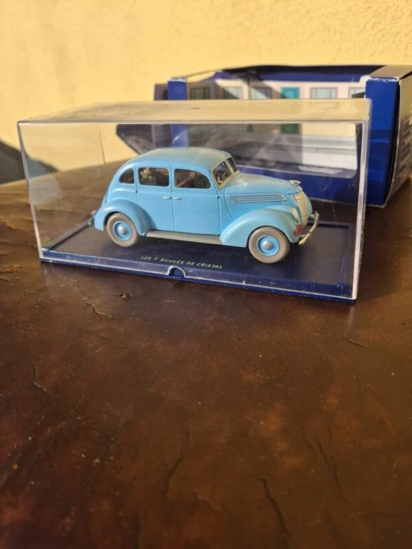 Lyseblå Tintin-taxi under klar udstillingskappe med æske bagved