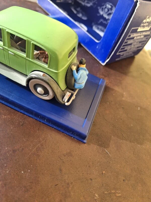 Tintin holder fast ved reservehjulet bag på Mitsuhiratos grønne sedan
