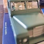 Grøn Tintin-Land Rover på blå sokkel med figurer i kabinen