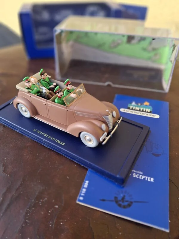Åben rosa-brun Ford V8 med Tintin og uniformerede figurer på blå sokkel
