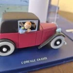 Nærbillede af Tintin ved sideruden på den røde modelbil