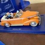 Orange åben New Delhi-taxi fra Tintin i Tibet med figurer på blå sokkel