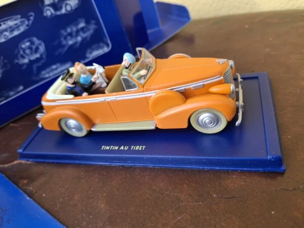 Orange åben New Delhi-taxi fra Tintin i Tibet med figurer på blå sokkel