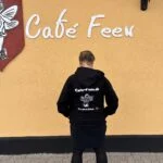 Café Feen hoodie vist bagfra under caféens skilt