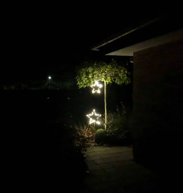 Stålstjerne på pind med lys som dekoration