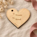 Hjerteformet gavemærke i lyst træ med graveret Til Trunte og Fra Knud på hør med rosa gavebånd.